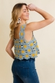 Woman with hand on forehead wearing blue daisy crochet top and blue jeans